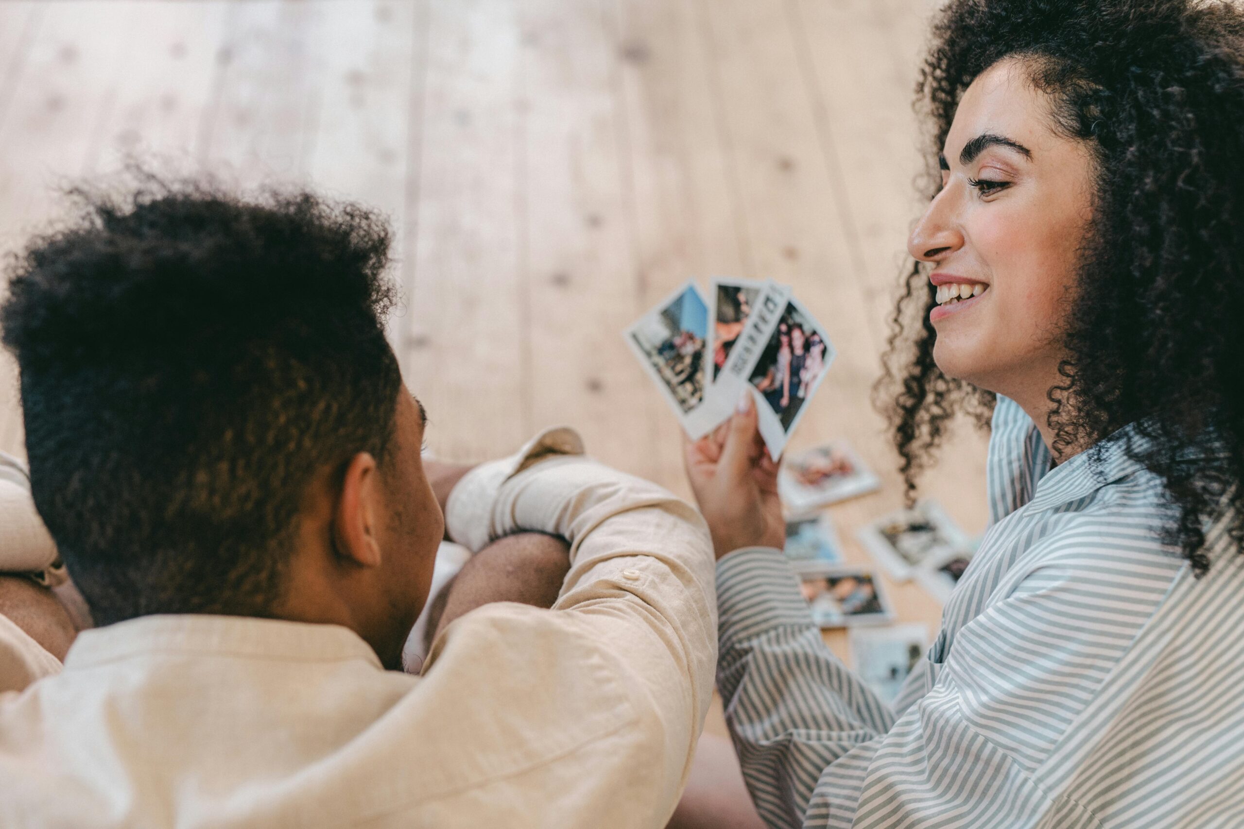 A happy couple sitting indoors, sharing cherished memories with instant photos.